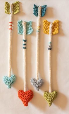 four crocheted hearts are hanging from the handles of canes in different colors