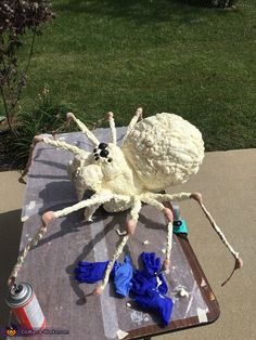 a large spider made out of yarn sitting on top of a table next to an empty can