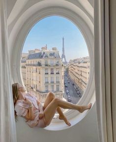 a woman laying in a window sill with the eiffel tower in the background