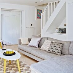 a living room filled with furniture next to a stair case in a home magazine cover