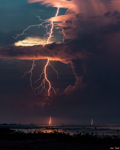 the sky is filled with lightning as it moves through the dark clouds over the ocean