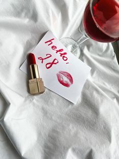 a glass of wine next to a piece of paper with lipstick on it