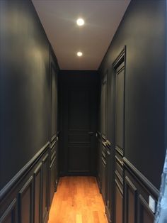 an empty hallway with black walls and wooden floors