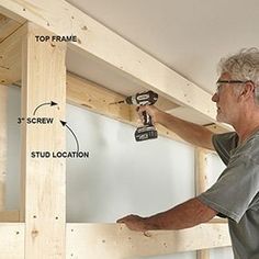 a man is working on the framing of a wall with a drill and screwdriver