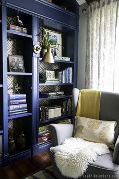 a living room with blue bookcases and white fur rug on the hardwood floor