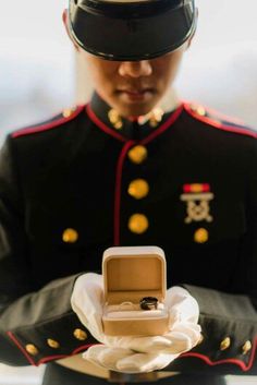 a man in uniform holding a ring with a box on his lap and wearing a hat