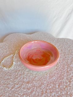 a pink bowl sitting on top of a white blanket