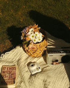 a basket full of flowers sitting on top of a blanket next to an old radio