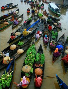 many boats filled with vegetables and people standing in the water next to eachother