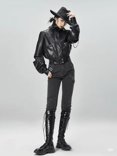 a woman in black clothes and boots is posing for a magazine cover shoot with her hands on her head