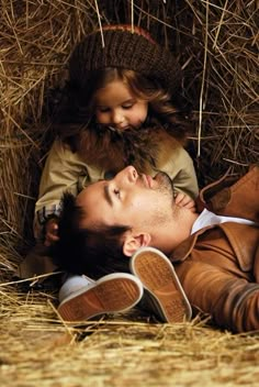 a man laying on top of a woman next to hay