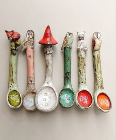 five spoons with different designs and colors are lined up in a row on the wall