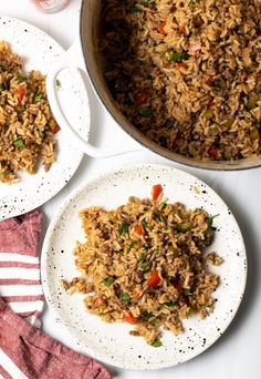 two white plates with rice and vegetables on them next to a red striped dish towel