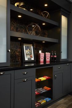 a kitchen with black cabinets and shelves filled with candy, candies, and snacks