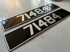 two black and white license plates sitting on top of a marble counter next to each other