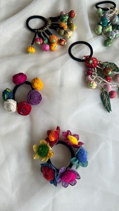 three different types of hair ties on a white sheet with flowers and leaves attached to them