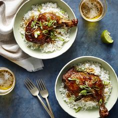 two white bowls filled with rice and meat on top of a blue tablecloth next to silverware