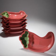 a stack of pink and green dishes sitting next to each other on a white surface