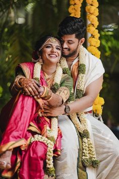 a man and woman sitting next to each other in front of some yellow garlands