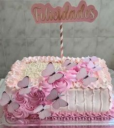 a pink cake with butterflies on it and a sign that says felifiedales