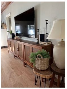 a large flat screen tv sitting on top of a wooden entertainment center next to a lamp