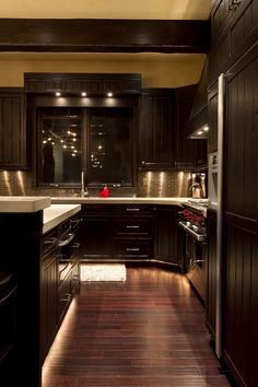 a kitchen with dark wood cabinets and white counter tops is lit by recessed lights