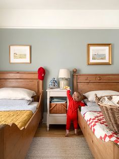 two beds in a room with pictures on the wall and one has a teddy bear