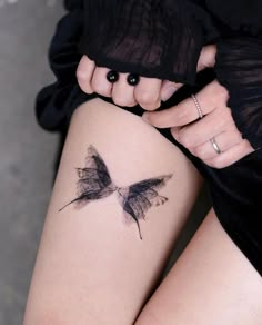 a woman's leg with a butterfly tattoo on her left thigh and the other arm behind her