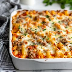 a casserole dish with meat and cheese in it on a towel next to some parsley