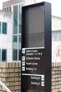 a black sign sitting on the side of a brick wall next to a tall building