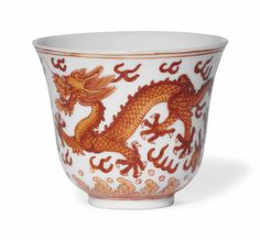 an orange and white porcelain bowl with a dragon design on the side, sitting in front of a white background