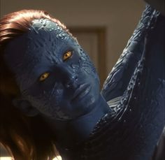 a close up of a person with blue skin and yellow eyes holding something in their hand