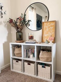 a white shelf with baskets on top and a mirror above it