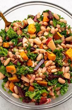 a salad with beans, carrots and lettuce in a glass bowl