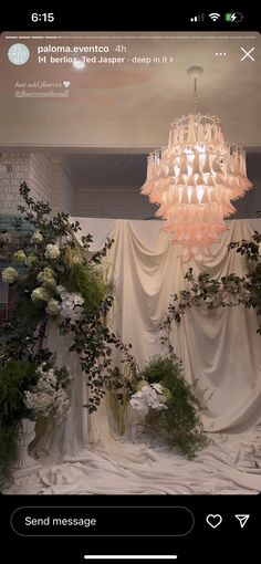 a chandelier hanging from the ceiling with flowers in vases and greenery