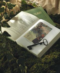 an open book sitting on top of a lush green field next to a pair of scissors