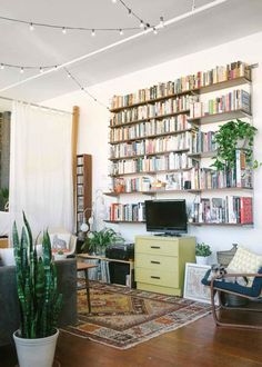 a living room filled with furniture and lots of books on the shelves next to a tv