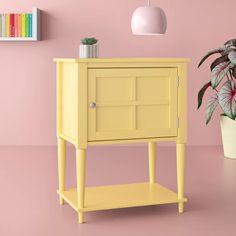 a small yellow cabinet next to a potted plant