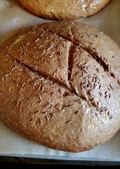 two loaves of bread sitting on top of a piece of wax paper next to each other