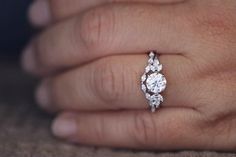 a woman's hand with a diamond ring on her left hand and the other hand holding an engagement ring