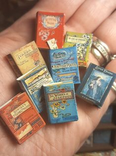 a person holding several small matchboxes in their hand, all different colors and sizes