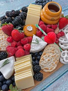 an assortment of cheeses, crackers and berries are arranged on a platter