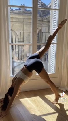 a woman doing a handstand in front of a window