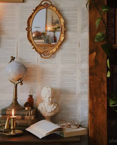 a table with a mirror, lamp and books on it in front of a wall