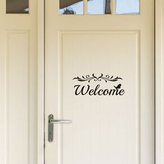 a welcome sign on the front door of a house that is painted white with black lettering