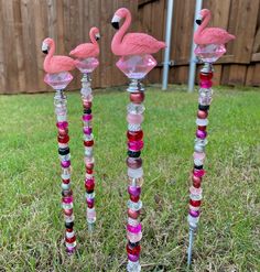 three pink flamingos sitting on top of each other in front of a wooden fence