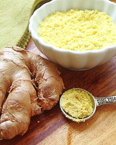 a wooden table topped with a bowl of yellow stuff and a spoon next to it