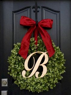 a black door with a red bow and monogrammed wreath