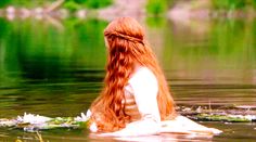 a woman with long red hair sitting in the water