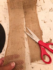 a pair of red scissors sitting on top of a piece of burlock